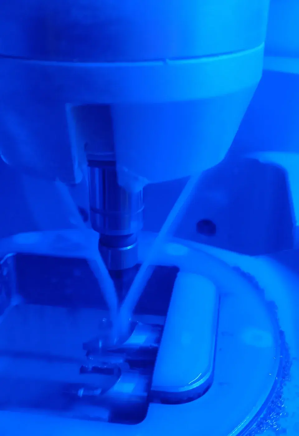 La fresatrice del laboratorio al lavoro su una struttura, nella luce blu della camera di fresaggio